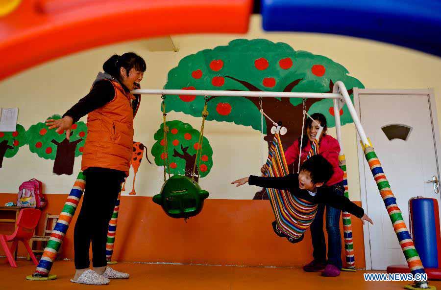 Teachers provide rehabilitation training to an autistic child in the An'an Autism Rehabilitation Center in Jinan, capital of east China's Shandong Province, Nov. 19, 2012. The center has received over 2,000 children with autism for rehabilitation treatment since its foundation in 2006. More than one-third of the children went to normal kindergartens and schools after 10-14 months' training here. (Xinhua/Guo Xulei) 