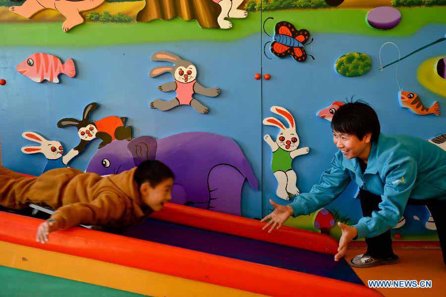 Teacher Fan Chuanyong helps an autistic boy to do rehabilitation training in the An'an Autism Rehabilitation Center in Jinan, capital of east China's Shandong Province, Nov. 19, 2012. The center has received over 2,000 autistic children for rehabilitation treatment since its foundation in 2006. More than one-third of the children went to normal kindergartens and schools after 10-14 months' training here. (Xinhua/Guo Xulei) 