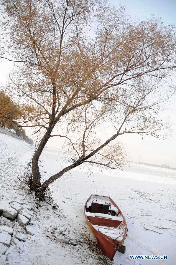 A snow-covered boat is seen on the frozen Songhua River in Harbin, capital of northeast China's Heilongjiang Province, Nov. 19, 2012. Navigation on the Harbin section of Songhua River has been closed since Monday, as the river entered frozen-up season due to the temperature plunge recently. (Xinhua/Wang Kai) 