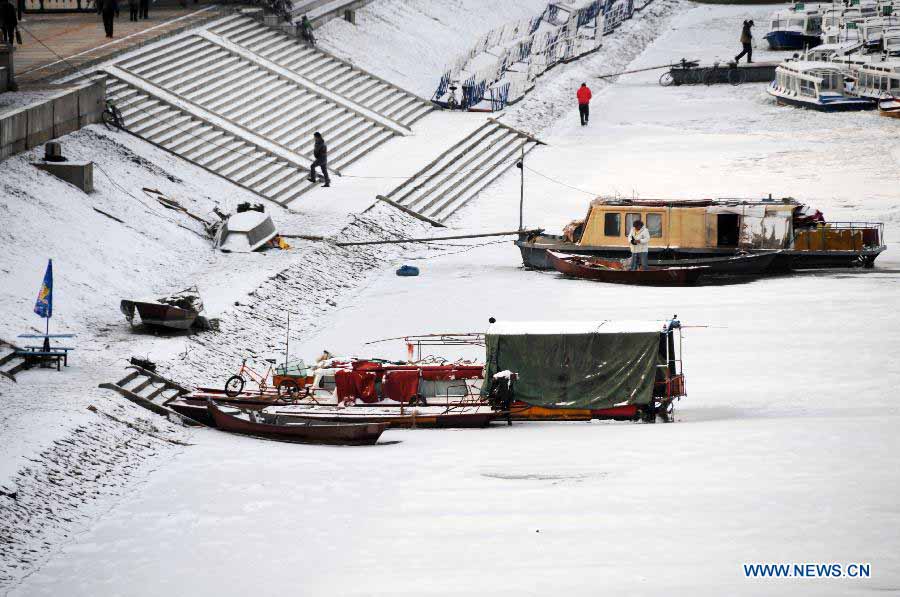 Snow-covered boats are seen on the frozen Songhua River in Harbin, capital of northeast China's Heilongjiang Province, Nov. 19, 2012. Navigation on the Harbin section of Songhua River has been closed since Monday, as the river entered frozen-up season due to the temperature plunge recently. (Xinhua/Wang Kai) 