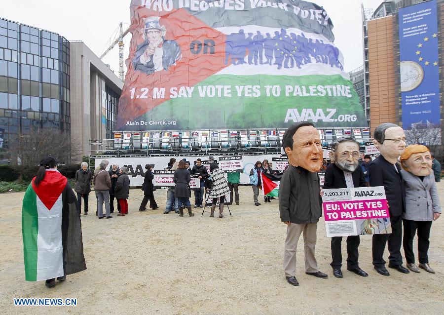 Activists wearing giant heads of German Chancellor Angela Merkel, French President Francois Hollande, Spanish Prime Minister Mariano Rajoy and British Prime Minister David Cameron (front R-L) attend a rally with a huge palestinian flag in front of EU headquarters in Brussels, Belgium, Nov. 19, 2012. Demonstrators installed the giant flag to urge EU backing the Palestinian membership in the United Nations. (Xinhua/Zhou Lei) 