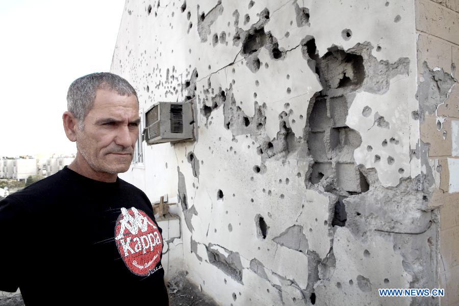Baruch Zohar, an Israeli resident, looks at his damaged house in Ofakim, south Israel, after being hit by a rocket fire from Gaza on Nov. 19, 2012. (Xinhua/Ariel Jerozolimski) 