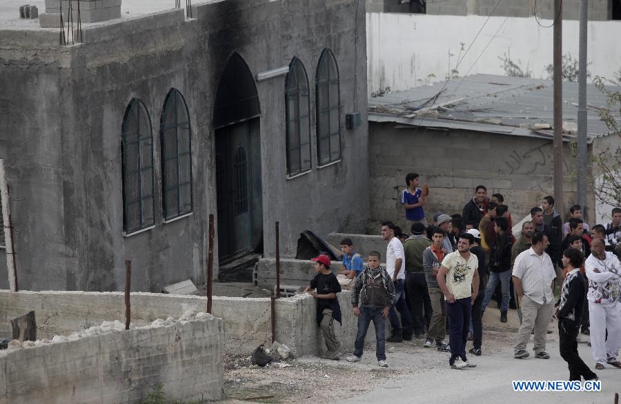 Palestinians stand in front of a mosque which has been burnt by Israeli settlers from Yitzhar settlement in the West Bank city of Nablus on Nov. 19, 2012. (Xinhua/Ayman Nobani)