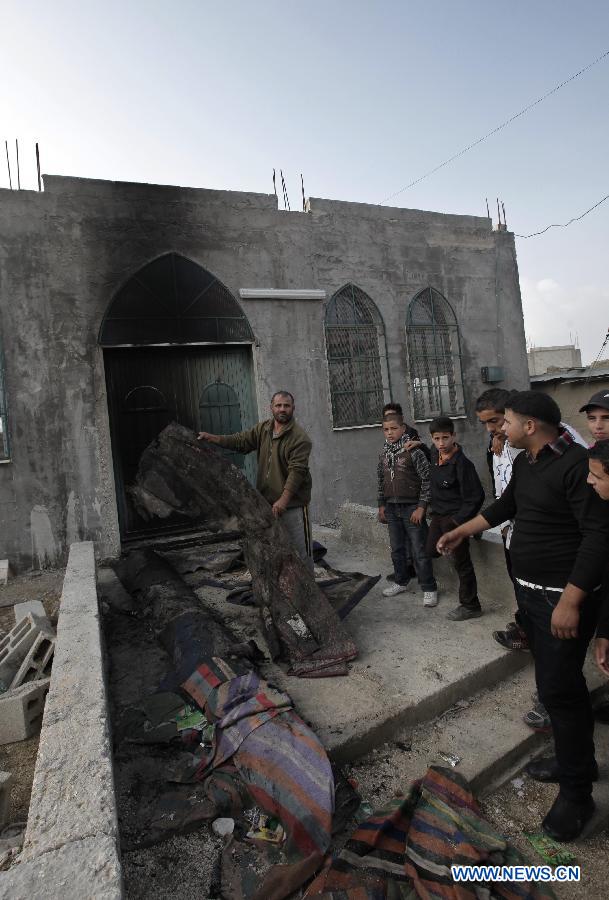 Palestinians stand in front of a mosque which has been burnt by Israeli settlers from Yitzhar settlement in the West Bank city of Nablus on Nov. 19, 2012. (Xinhua/Ayman Nobani)