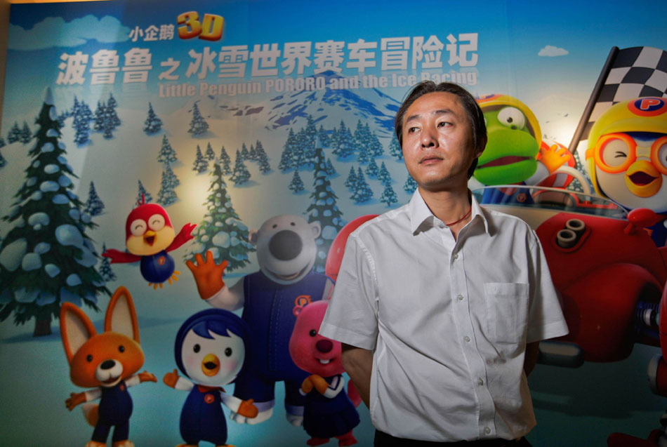 Wang Jin stands before a poster of an animation film in the production base of the Program Production Center of China ACG Group Co., Ltd in Xiamen, southeast China's Fujian Province, June 15, 2012. (Xinhua/Meng Chenguang)