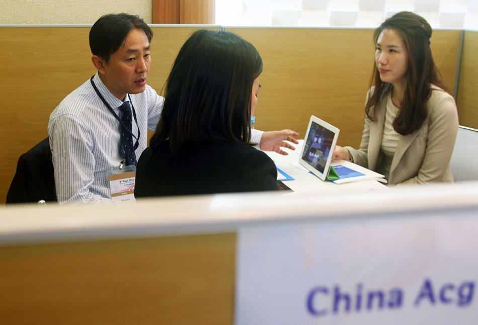 Wang Jin (L) negotiates business with a client during an animation fair held in Seoul, South Korea, April 12, 2012. (Xinhua/Meng Chenguang)