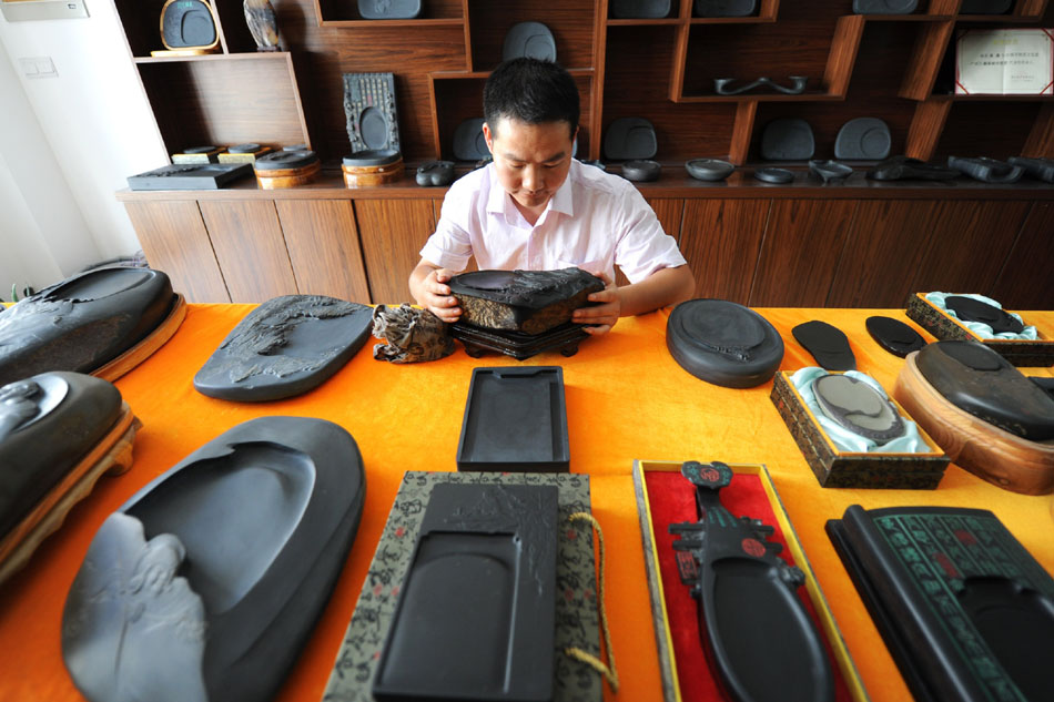 Wen Xin cleans the inkstone carvings in the showroom in Shexian County of east China's Anhui Province, Aug. 7, 2012. (Xinhua/Du Yu)