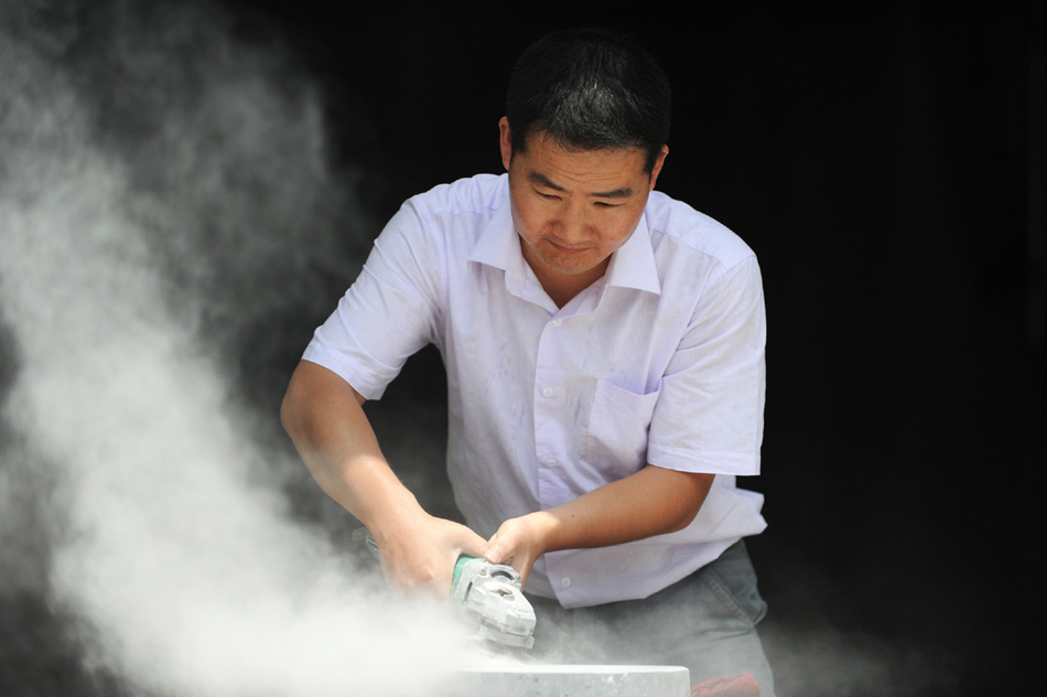 Wen Xin cuts inkstones in a studio in Shexian County of east China's Anhui Province, Aug. 7, 2012. (Xinhua/Du Yu)