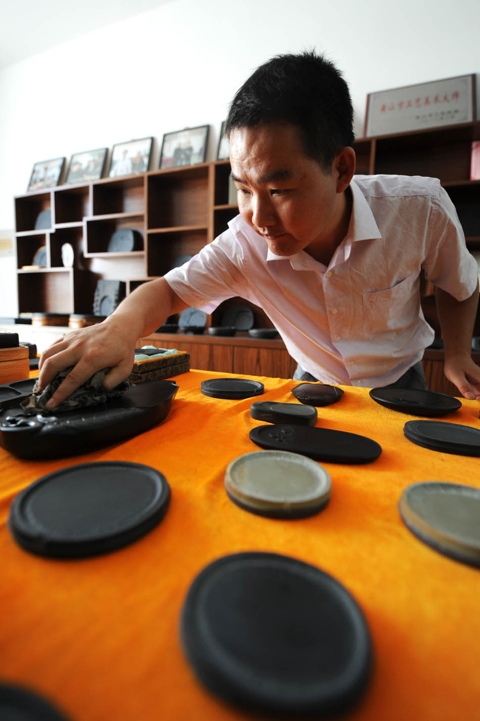 Wen Xin cleans the inkstone carvings in the showroom in Shexian County of east China's Anhui Province, Aug. 7, 2012. (Xinhua/Du Yu)