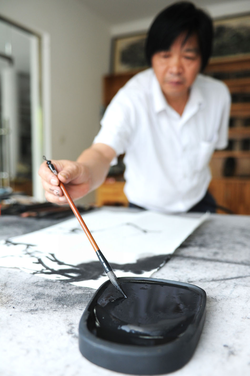 Painter Yao Laiyou draws a painting with an inkstone made by Wen Xin in Shexian County of east China's Anhui Province, Aug. 8, 2012. (Xinhua/Du Yu)