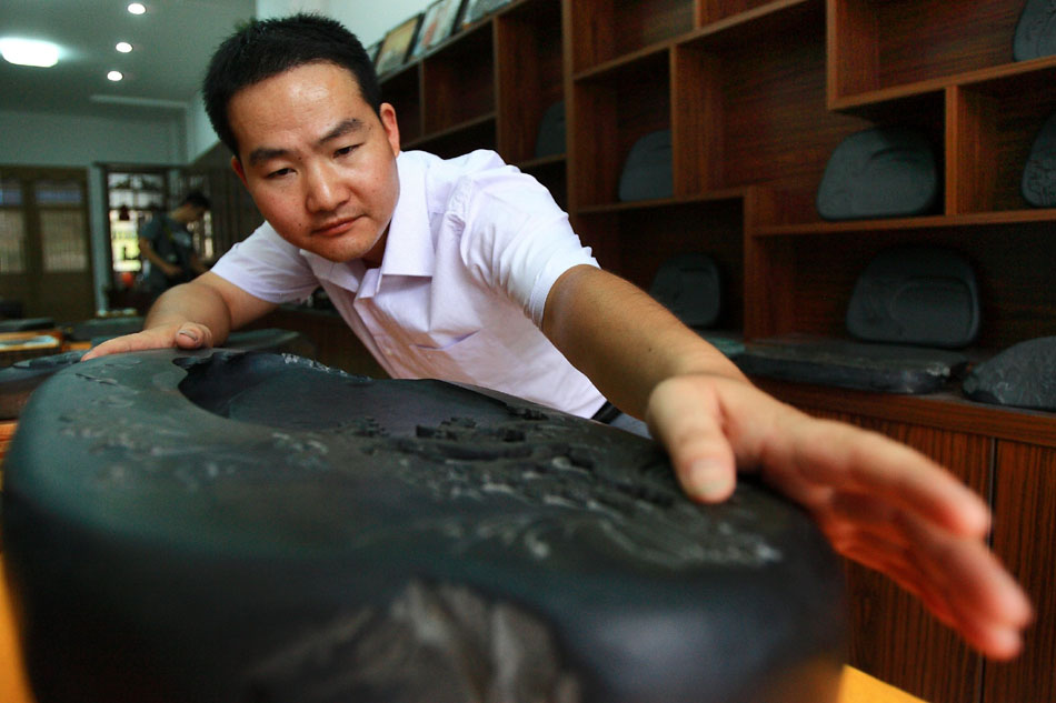Wen Xin examines an inkstone carving in the showroom in Shexian County of east China's Anhui Province, Aug. 7, 2012. (Xinhua/Xu Zijian)
