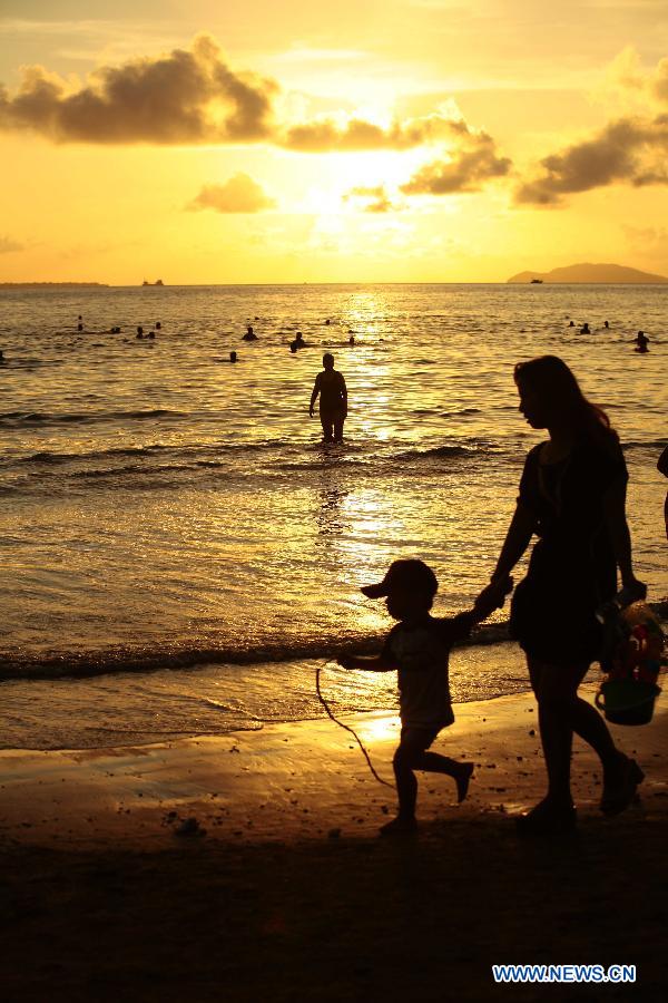 Tourists play on a beach during the sunset in Sanya, south China's island of Hainan Province, Nov. 20, 2012. Though the winter draws near, the tropic seaside city of Sanya remains warm and attracts many tourists. (Xinhua/Chen Wenwu) 