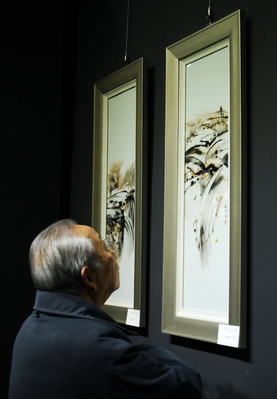 Porcelain artist Wang Xiliang visits a solo exhibition of Li Bin in Jingdezhen, east China's Jiangxi Province, Dec. 31, 2011. (Xinhua/Wan Haiping)