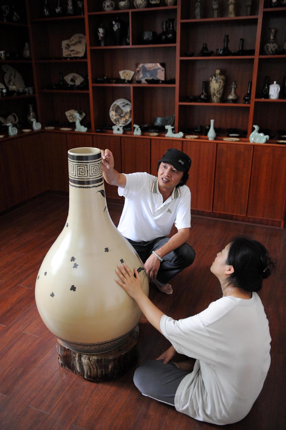 Li Bin (L) discusses porcelain art with a friend at a workroom in Jingdezhen, east China's Jiangxi Province, Aug. 18, 2012. (Xinhua/Zhang Ruiqi)