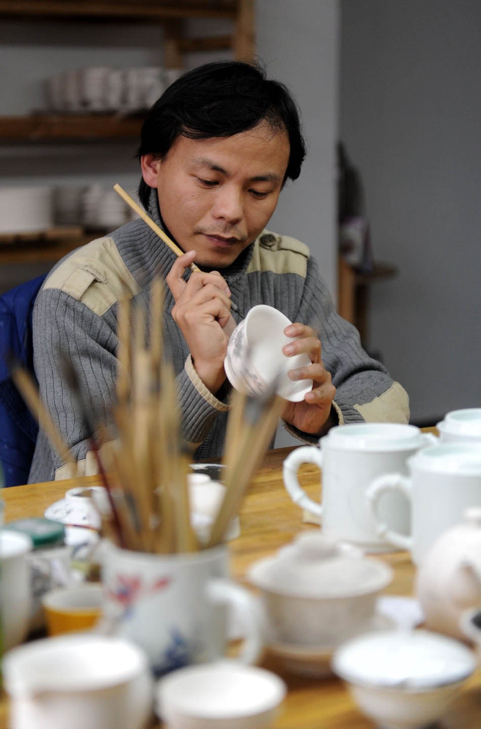 Liu Zhen paints on a  porcelain adobe in his studio at the Chengdexuan Porcelain Co.,Ltd, in Jingdezhen of east China's Jiangxi Province, March 8, 2012. (Xinhua/Zhou Ke)