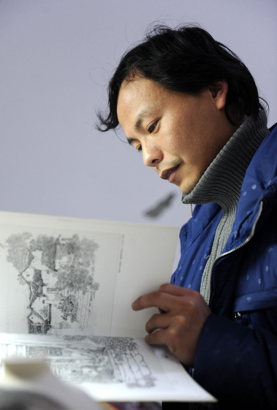 Liu Zhen studies a picture copybook in his studio at the Chengdexuan Porcelain Co.,Ltd, in Jingdezhen of east China's Jiangxi Province, March 8, 2012. (Xinhua/Zhou Ke)