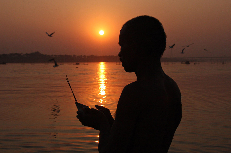 Holding the setting sun: A man prays a hope beyond the river, in Allahabad, India on Nov.13, 2012. (Xinhua/AFP)
