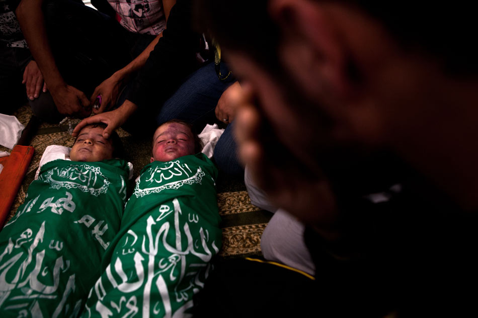 A Hijazzi family member wipes tears near the bodies of Hijazzi's sons during a funeral in Gaza City, Nov. 20, 2012. Israeli fighter jets hit a house in northern Gaza Strip Monday evening, killing a father and two sons and wounding 12 others, witnesses and medical sources said. The house in Beit Lahiya town was destroyed while the father, Fouad Hijazzi, died along with his two sons, aged four and two respectively. (Xinhua/Chen Xu) 