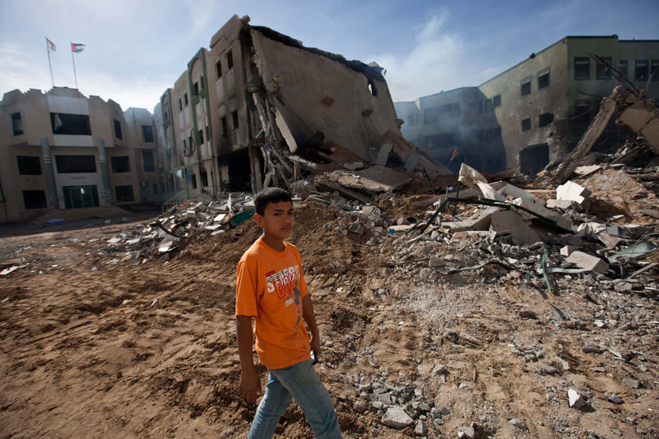A Palestinian boy walks past the ruins of buildings destroyed by Israeli air strikes in Gaza City, on Nov. 16, 2012. (Xinhua/Chen Xu)