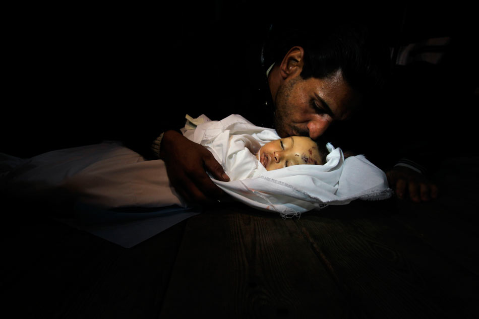A sad man kisses the baby girl in mortuary of a hospital in Gaza City, on Nov. 15, 2012. (Xinhua/AFP)