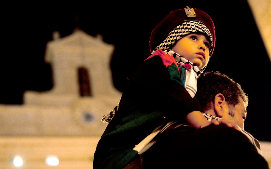 A child sitting on the shoulder of his father joins the demonstration against Israeli attack on the Gaza Strip in Rome, capital of Italy, on Nov. 16, 2012. (Xinhua/AFP)