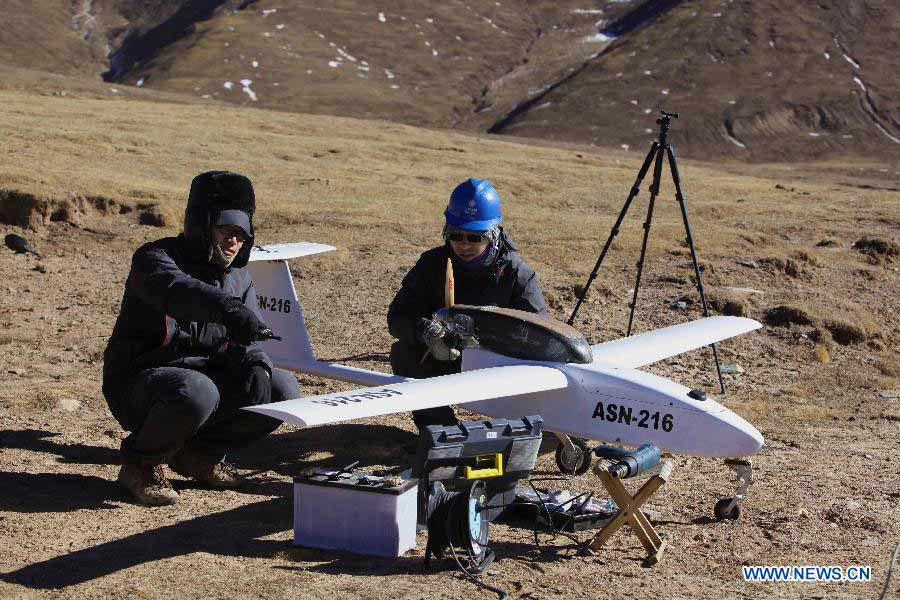 Technicists from the Shandong Electric Power Research Institute (SEPRI) examine an unmanned aircraft which is designed to inspect power transportation lines in regions of high altitude, during a test in Guide County of Qinghai, a province on the Qinghai-Tibet Plateau, northwest China, Nov. 21, 2012. A research team of the SEPRI has recently conducted a flight test of unmanned aircrafts over the ground with altitude of 4,500 meters, which marks the end of the first round of the unmanned aircraft test project for inspecting power transportation lines on plateaus. (Xinhua) 