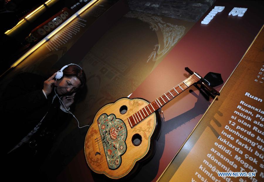 A visitor listens to the music of the instrument Ruan at "The Colors of Dunhuang: A Magic Gateway to the Silk Road" exhibition held in Mimar Sinan University in Istanbul of Turkey, on Nov. 20, 2012. The Exhibition kicked off here on Tuesday. (Xinhua/Ma Yan)