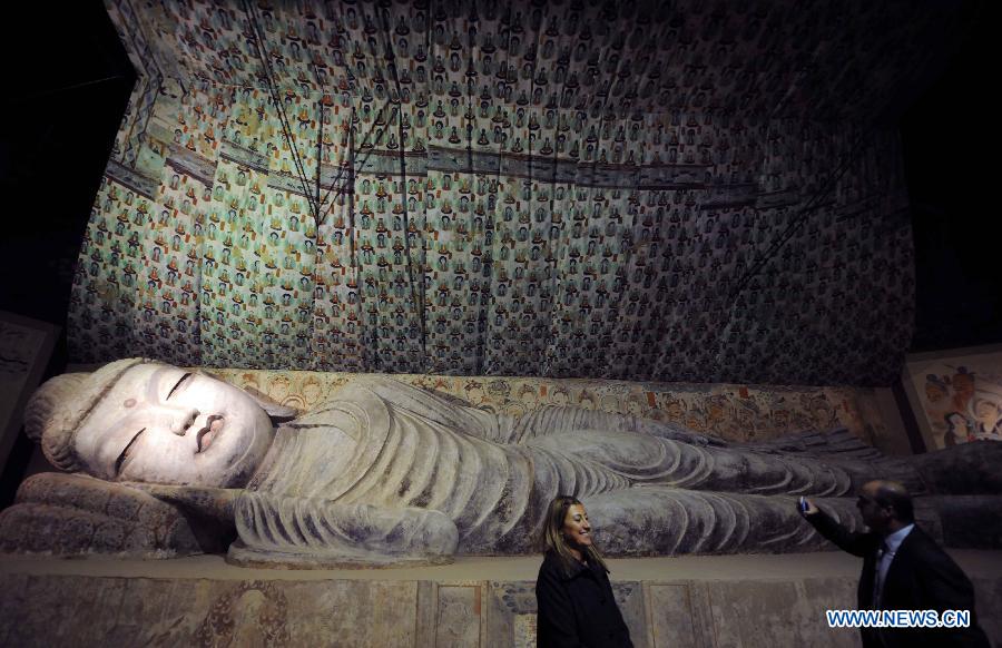 A visitor poses for photos in front of the duplicate of a Buddha statue at "The Colors of Dunhuang: A Magic Gateway to the Silk Road" exhibition held in Mimar Sinan University in Istanbul of Turkey, on Nov. 20, 2012. The Exhibition kicked off here on Tuesday. (Xinhua/Ma Yan)