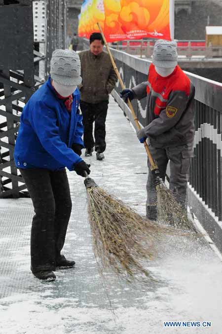 Two sanitation workers sweep snow in Lanzhou, capital of northwest China's Gansu Province, Nov. 22, 2012. The province was hit by snow and temperature decrease on Thursday.(Xinhua/Fan Peishen) 