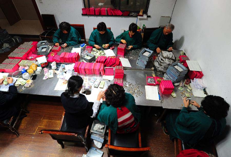 Staff members at the cash center of the Taicang Public Bus Company sort notes and coins at the cash center of the Taicang Public Bus Company in Taicang, east China's Jiangsu Province, Nov. 18, 2012. Each day, staff members at the cash center of the Taicang Public Bus Company need to sort out notes and coins collected from all bus fare boxes of the company. It takes four hours on average to finish a day's work: the total earnings of 52 bus lines. (Xinhua/Ji Haixin) 