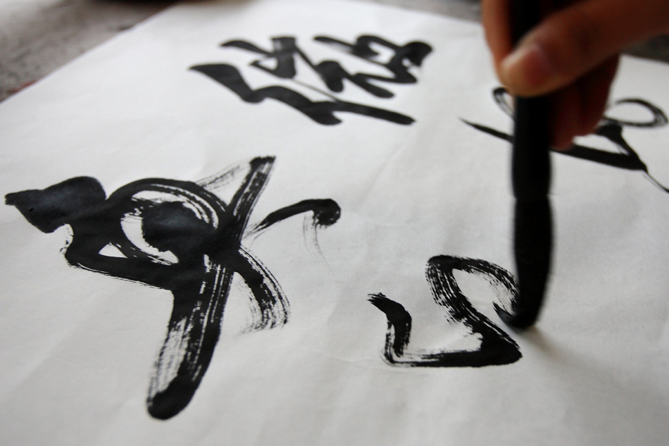 A customer writes with the ink grinded from the inksticks made by Xiang Shengli in Shexian County of east China's Anhui Province, Aug. 8, 2012. (Xinhua/Xu Zijian)