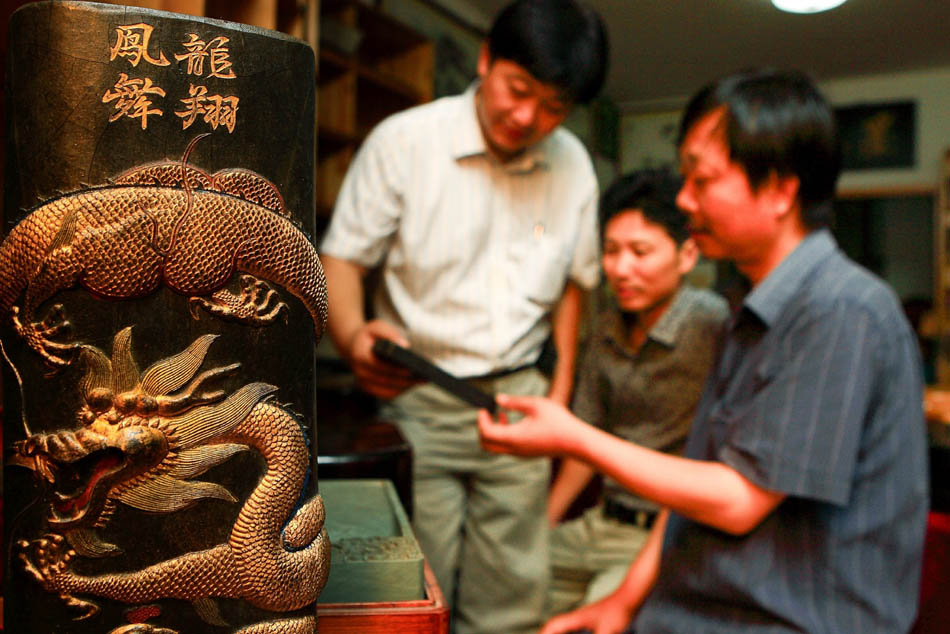 Xiang Shengli (1st L) introduces a piece of inkstick he made to the customers in Shexian County of east China's Anhui Province, Aug. 8, 2012. (Xinhua/Xu Zijian)