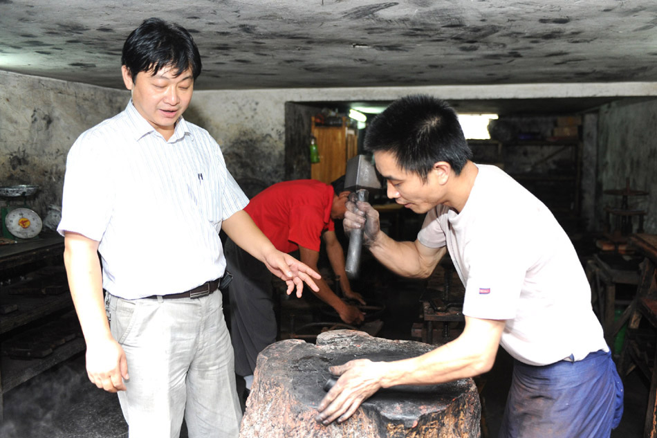 Xiang Shengli guides the other craftsmen to make inksticks in Shexian County of east China's Anhui Province, Aug. 11, 2012. (Xinhua/Du Yu)