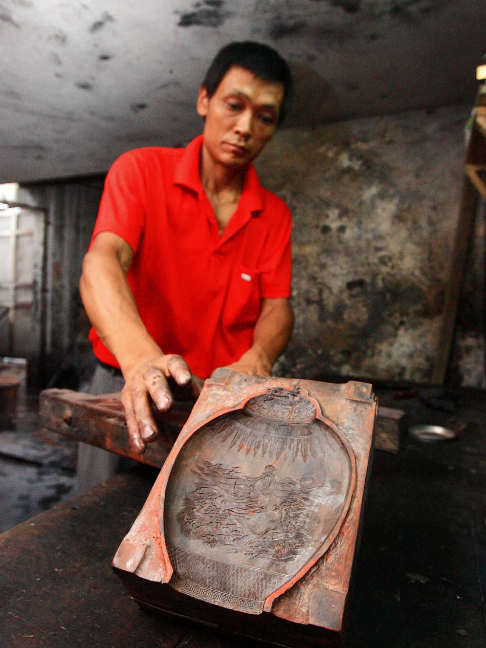 Wang Yongzhong, a worker of Xiang Shengli's studio, stuffs the raw material of inkstick into a mould in Shexian County of east China's Anhui Province, Aug. 8, 2012. (Xinhua/Xu Zijian)