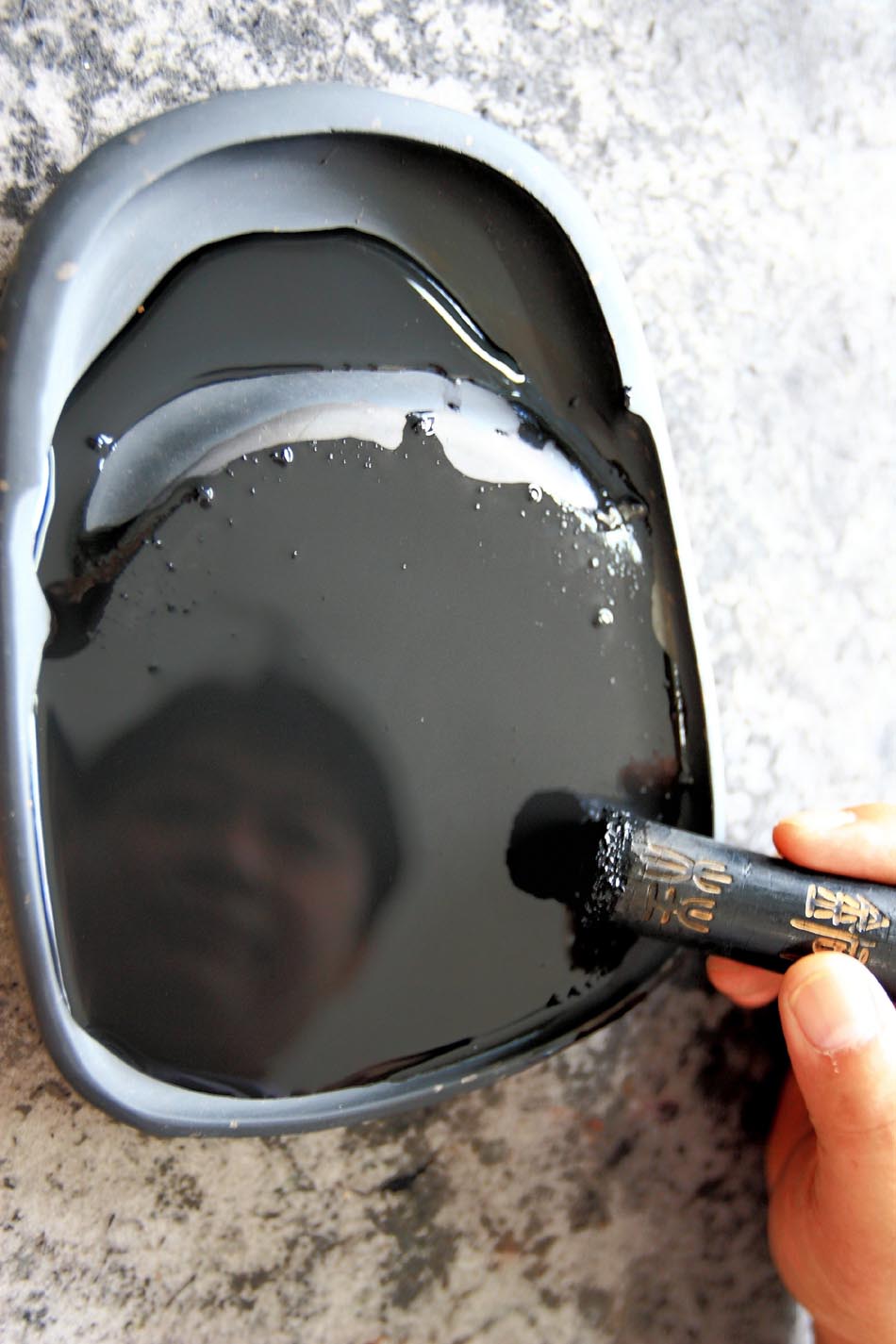Xiang Shengli grinds a piece of inkstick he made for a customer to examine the quality in Shexian County of east China's Anhui Province, Aug. 8, 2012. (Xinhua/Xu Zijian)
