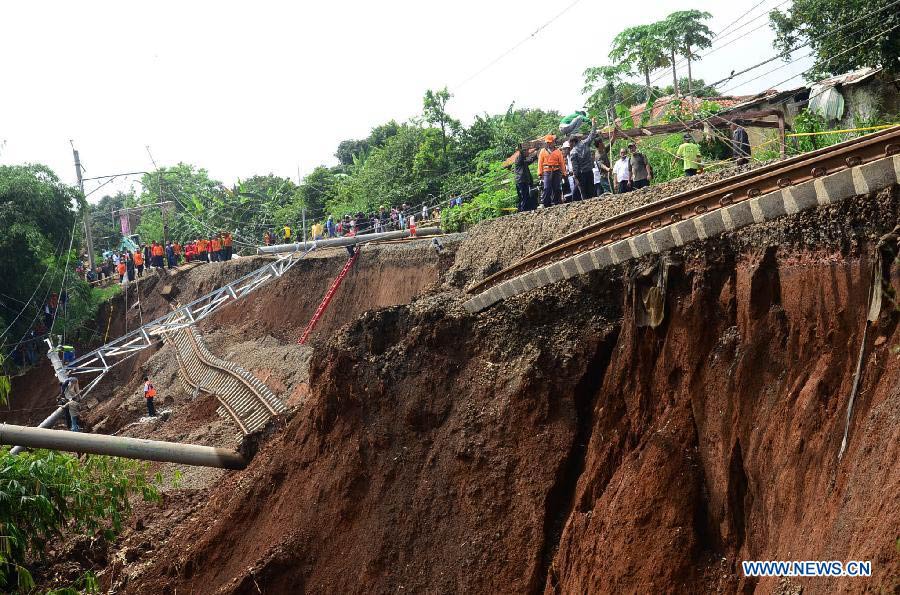 Staff members try to fix railway and electric wires broken in a landslide in Bogor, Indonesia, Nov. 22, 2012. Landslide caused by rainfall Wednesday night destroyed rails and led to the cancel of 98 flights. (Xinhua/Dwi)