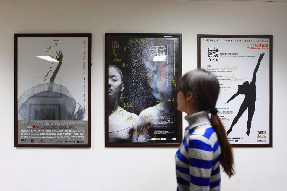 A dancer walks past the posters showing the dance works of Beijing Dance Theatre (BDT) in Beijing, capital of China, March 4, 2012. (Xinhua/Xu Zijian)