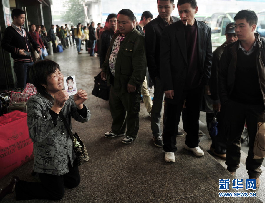 Yu Fanglan, aged over 70, kneels in front of the ticket office of North Coach Station of Fuzhou holding a picture of her lost grandson on Nov. 22, 2012. She was there to ask for help to find her 12-year-old grandson who disappeared three months ago.  Her grandson Zheng Biran went missing after visiting a friend on Aug.26, 2012. (Xinhua)