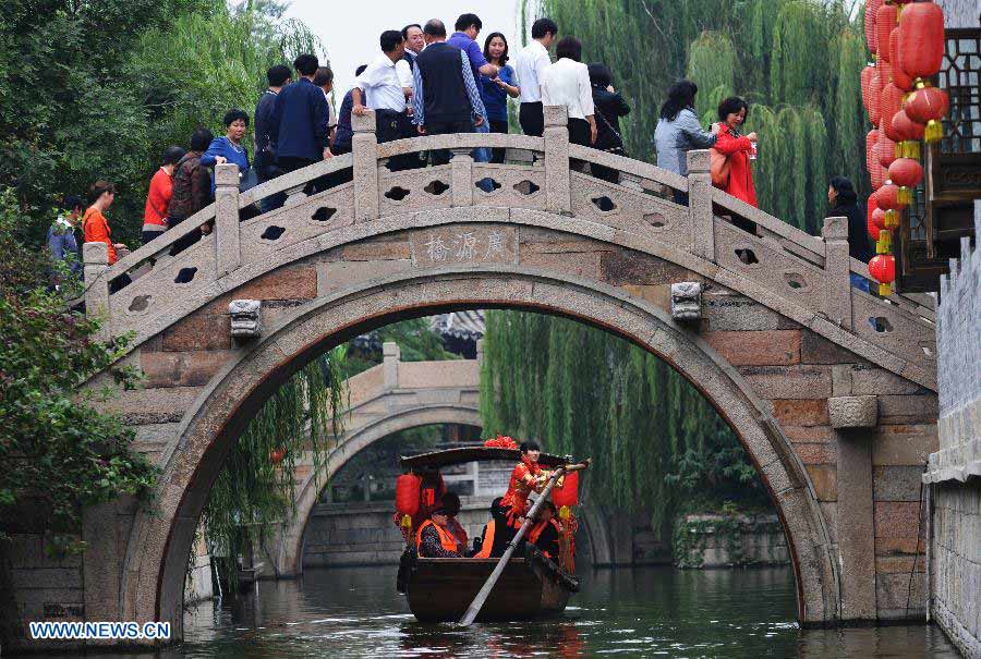File photo taken on Oct. 5, 2012 shows tourists traveling around Tai'erzhuang ancient city in Zaozhuang, east China's Shandong Province. Tai'erzhuang ancient city was approved to be the national 5A-level tourist area on Nov. 22, 2012. (Xinhua/Gao Qimin) 