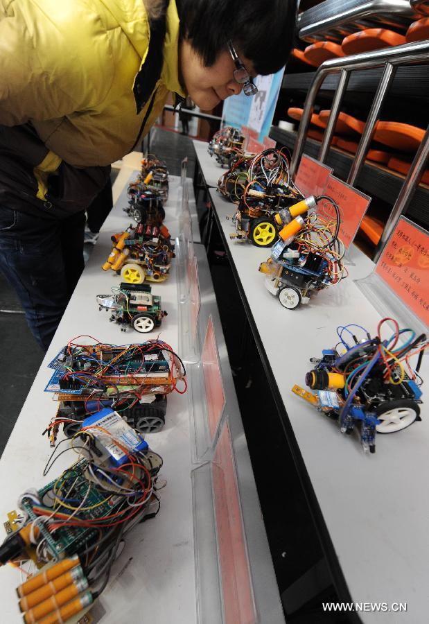 A visitor views robots awarded in a design competition during a robot show held in Qingdao University, Qingdao, east China's Shandong Province, Nov. 25, 2012. The robot show, the first kind of this exhibition in Shandong, showcased the latest achievement of robot-related technology, involving over 100 exhibits from home and abroad. (Xinhua/Guo Xulei) 