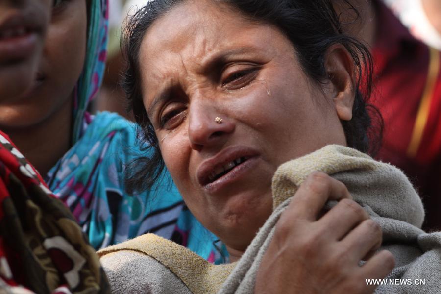 A woman cries over the loss of her husband after a fire accident in a garment factory in Saver, outskirts of Dhaka, Bangladesh, Nov. 25, 2012. It is believed that over 100 people died in the accident, said police. (Xinhua/Shariful Islam) 