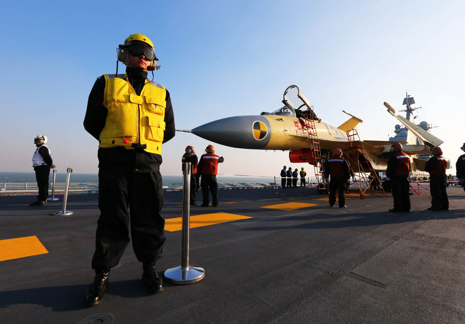 Staff members check a carrier-borne J-15 fighter jet on China's first aircraft  carrier, the Liaoning. (Xinhua/Cha Chunming)