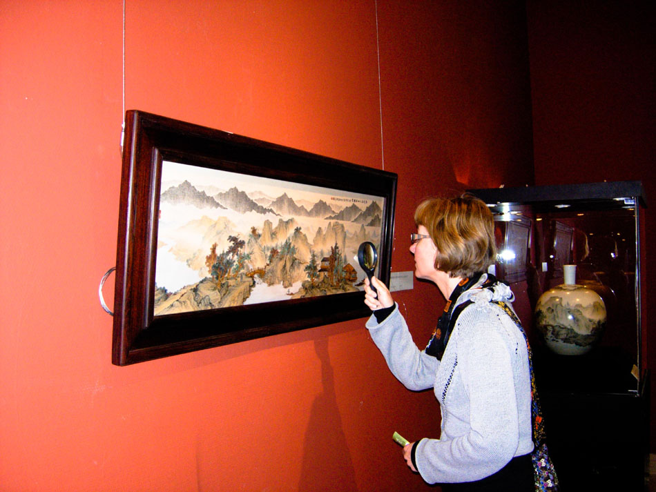An undated photo shows a foreigner viewing a miniature calligraphic creation by Wang Zhiwen. (Xinhua)