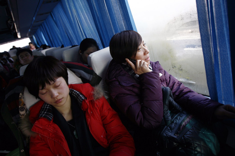 Wu Fenghua calls her son on a bus journey for a village night show in Yueqing Village in Wenzhou, east China's Zhejiang Province, Feb. 3, 2012. (Xinhua/Cui Xinyu)