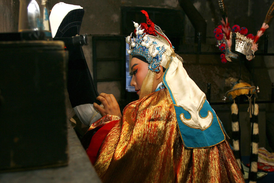 Wu Fenghua stretches her leg before going on stage at a night show in Shengzhou, east China's Zhejiang Province, Jan. 28, 2012. (Xinhua/Cui Xinyu)