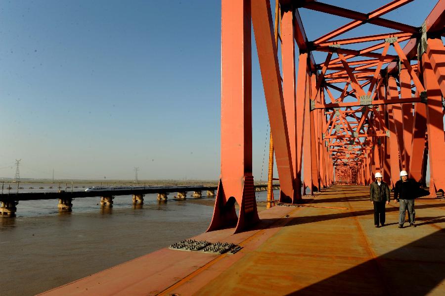 Several workers walk at the construction site of the Beijing-Guangzhou Railway bridge across the Yellow River in Zhengzhou, capital of central China's Henan Province, Nov. 26, 2012. The bridge, which is projected to be completed by the end of 2013, is the 6th Yellow River bridge planned to be built in Zhengzhou. (Xinhua/Zhu Xiang)