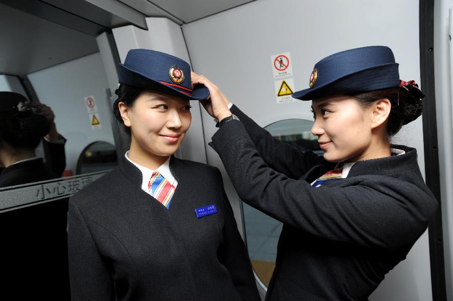A railway attendant helps a colleague dress up in Shenyang, capital of northeast China's Liaoning Province, Nov. 26, 2012. The Shenyang Railway Bureau has launched training programmes for bullet train attendants who will be working on the Harbin-Dalian High-Speed Railway, scheduled to open on Dec. 1, 2012. The 921-km Harbin-Dalian High-Speed Railway is the first rail line in China's freezing high-latitude regions. (Xinhua/Zhang Wenkui) 