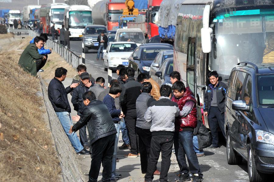 Passengers wait outside vehicle on the Jingtai Highway in Jinan, east China's Shandong Province, Nov. 26, 2012. Several traffic accidents happened on the highway and caused a traffic jam on Monday. (Xinhua/Xu Suhui) 