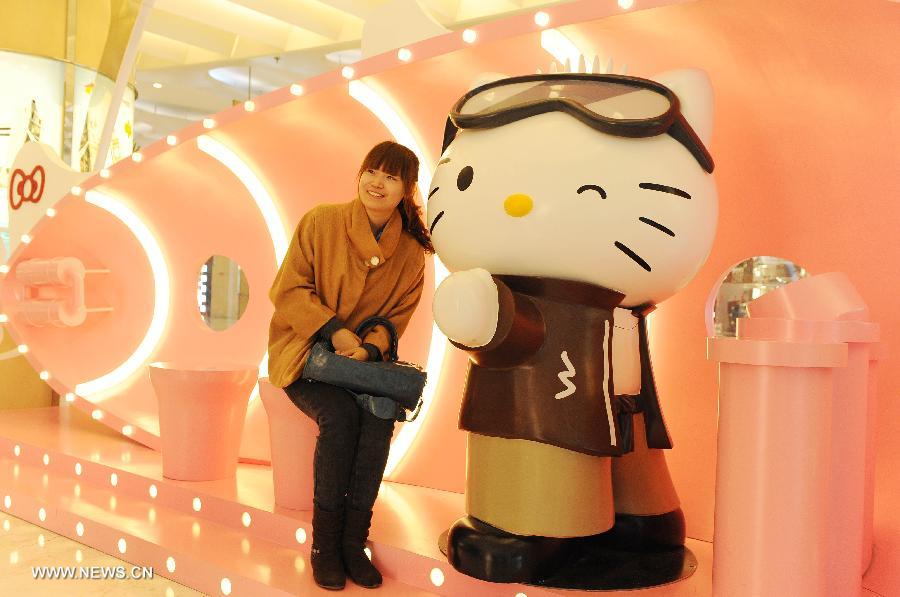 A young woman poses for pictures with a Hello Kitty in the Joy City in east China's Shanghai Municipality, Nov. 26, 2012. A big Hello Kitty exhibition themed on Hello Kitty's exploration in the polar regions would last from Nov. 24, 2012 to Feb. 24, 2013 in Shanghai. (Xinhua/Lai Xinlin) 