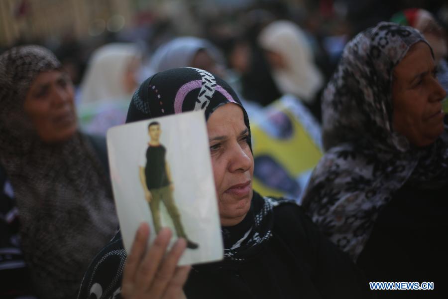 A Palestinian woman holds a poster of Palestinian prisoner during a protest calling for the release of them from Israeli jails and in support of prisoners on hunger strike in front of Red Cross, in Gaza city, on Nov. 26, 2012. Some 4,600 Palestinians prisoners are still in the Israeli prisons. (Xinhua/Wissam Nassar)